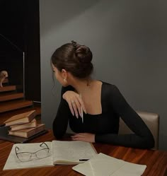 a woman sitting at a table with books and glasses