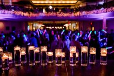 candles are lined up on a table with people in the background