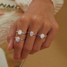 a woman's hand with three different rings on her fingers and one has an engagement ring