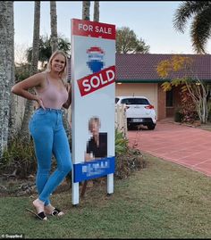 a woman standing next to a sold sign