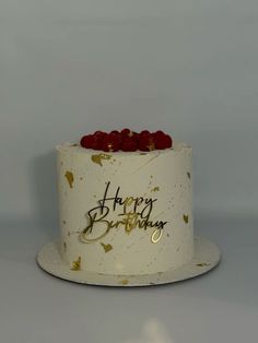 a white birthday cake with red roses on top and happy birthday written on the side