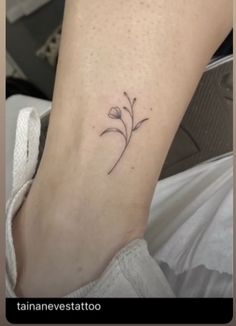 a small flower tattoo on the left ankle is shown in black ink, and it looks like