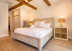 a bedroom with white bedding and wooden beams