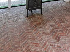 a stove sitting on top of a red brick floor next to a glass wall with an open door