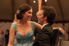 a man in a suit and tie standing next to a woman with a flower in her hair