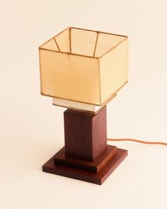 a lamp that is sitting on top of a wooden stand with a light bulb in the middle