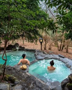 two people sitting in a hot tub surrounded by trees