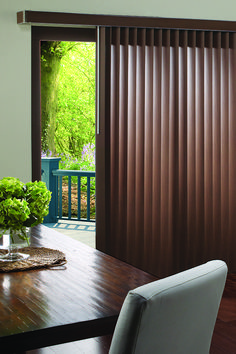 a dining room table with a vase of flowers on it next to a sliding glass door