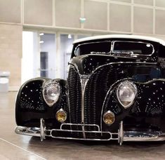 an old black car is parked in a building