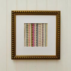 a framed art piece hanging on the wall next to a white striped wallpapered wall