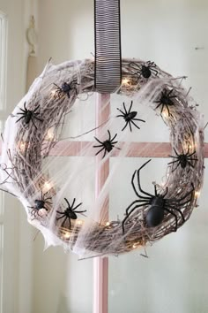 a wreath with spider webs hanging from it's sides and lights on the outside