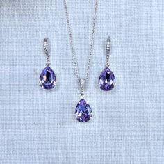 This beautiful handmade small and delicate teardrop dangle bridal earrings, necklace and bracelet feature Dark Violet European crystal pear shaped fancy stones. The small pear stones measure 10x14mm and are hand set in your choice of settings (rhodium (silvertone), yellow or rose gold). The earrings feature cz set french hooks, the necklace features a cz set bail and 18" 925 sterling silver chain and the bracelet features a lobster claw clasp with an extension chain. Really beautiful quality and Delicate Teardrop Crystal Jewelry, Anniversary Jewelry Sets With Sparkling Teardrop Stones, Anniversary Teardrop Jewelry Sets With Sparkling Stones, Teardrop Pendant Earrings With Sparkling Stones For Gift, Silver Teardrop Pendant Jewelry For Bridesmaid Gift, Sparkling Teardrop Earrings As A Gift, Teardrop Jewelry Sets With Matching Earrings For Anniversary, Cubic Zirconia Teardrop Jewelry For Bridesmaid Gift, Anniversary Teardrop Jewelry Set With Matching Earrings