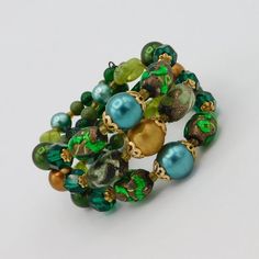 Pretty artisan made wire cuff bracelet easily fits a a 7-8 inch wrist.  Made with beautiful selection of irredescent green art glass beads, faceted green glass beads, satin finished beads and round glass beads about to finish out the ends.  Large beads of gold tone filigree bead caps.  The color combination is wonderful with bright green foil glass and varying shades of green and gold satin finished beads.  Bracelet is 1 1/4 inch wide and in very good vintage condition. Green Bohemian Stretch Bracelet With Faceted Beads, Green Stretch Bracelet With Faceted Round Beads, Bohemian Green Crystal Bracelet With Round Beads, Bohemian Green Crystal Round Bead Bracelet, Handmade Green Bangle For Party, Green Bohemian Stretch Bracelet With Large Beads, Adjustable Green Bangle For Party, Green Bohemian Bangle For Parties, Unique Green Bangle Bracelet