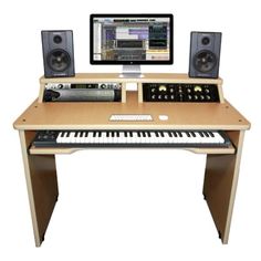 an electronic keyboard sitting on top of a wooden desk next to a computer monitor and speakers