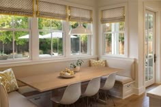 a dining room table with four chairs and a bench in front of the window that is open