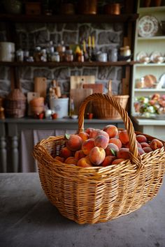 a wicker basket filled with peaches sitting on top of a table next to a shelf