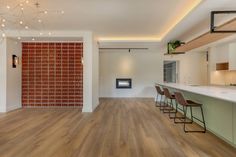 an empty kitchen and living room with wood flooring on the walls, lights hanging from the ceiling