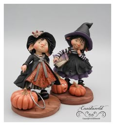 two figurines are dressed in black and orange outfits, one is holding a pumpkin