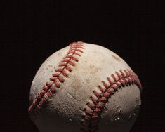 an old worn baseball with red stitching on the outside and black backround