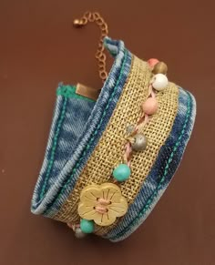 a close up of a bracelet on a brown surface with beads and other items attached to it