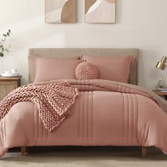 a bed with pink comforters and pillows in a bedroom