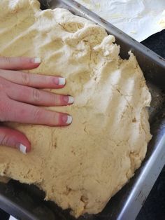 a person is kneading dough into a pan