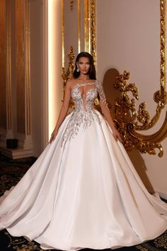 a woman in a white wedding dress standing next to a gold and black wall with a large mirror behind her