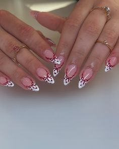 a woman's hands with pink and white nail designs on their nails, holding onto her manicures