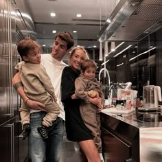 a man, woman and two children posing for a photo in front of a kitchen counter