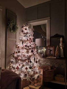 a white christmas tree is lit up in the living room with other decorations and presents