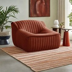 an orange chair sitting on top of a rug in a living room next to a potted plant