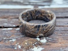 a wooden ring sitting on top of a piece of wood with white and brown paint