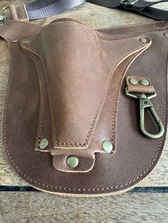 a brown leather purse with metal handles on a wooden table