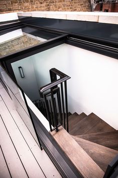 the stairs are made of wood and have black railings on them, along with a glass door