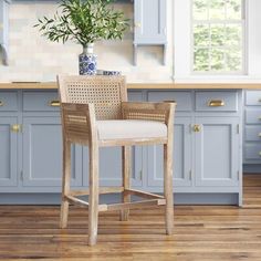 a kitchen with blue cabinets and white counter tops is pictured in this image, there is a plant on the bar stool