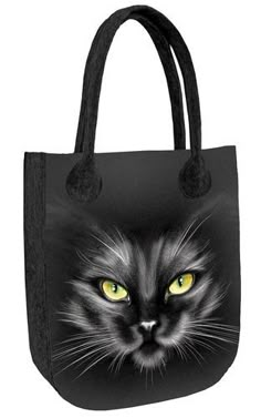 a black and white cat with yellow eyes on a black tote bag that has the image of a black cat's face painted onto it