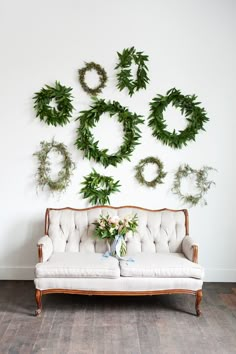 a couch sitting in front of a wall with wreaths hanging on it's side