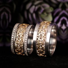 two wedding bands with gold and silver filigrees are shown on a black surface