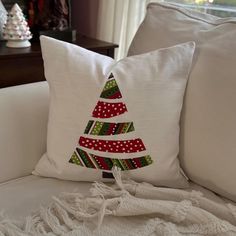 a christmas tree pillow sitting on top of a white couch