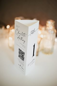 a close up of a white box on a table with candles in the back ground