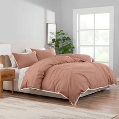 a bed in a room with a plant on the side and a window behind it