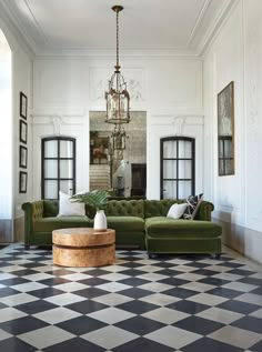 a living room with green couches and black and white checkered tile flooring