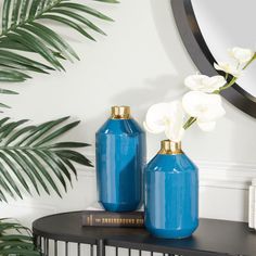 two blue vases sitting on top of a table next to a mirror and potted plant