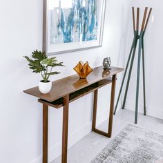 a wooden table with a potted plant sitting on top of it next to a painting