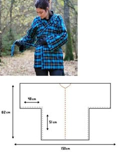 a woman wearing a blue and black plaid shirt standing in the woods with her hands on her hips