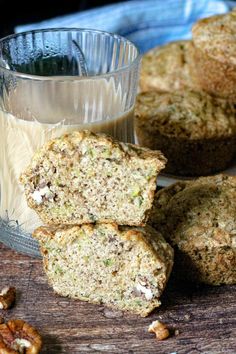 several muffins on a wooden table next to a cup of milk and nuts