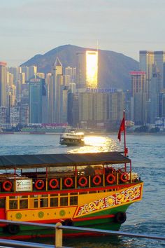 a yellow and red boat floating on top of water near a large cityscape