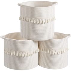 three white baskets with tassels are stacked on top of each other, one is empty