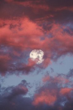 the full moon is seen through some clouds