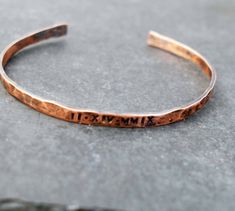 Our delicate copper bracelet is hand forged from rich jewelers copper. The bangle style cuff has been hammered, polished and oxidized giving it a warm, rich patina.A perfect gift with your special date stamped in Roman Numerals.The cuff is beautiful worn alone or stacked with others. I wear one with the coordinates of my daughter's birthplace and another with her birthdate.Copper is the traditional 7th or 22nd wedding anniversary gift, but this is lovely for any occasion.To maintain  the patina Handmade Copper Bangle Bracelets, Hand Forged Copper Bangle Bracelet, Hammered Copper Bangle Bracelets, Hammered Copper Bangle Bracelet, Gold Electroformed Bracelets For Gift, Hammered Rose Gold Cuff Bracelet Gift, Engraved Copper Bracelet Jewelry, Bronze Hammered Bracelet As Gift, Copper Bangle Gift